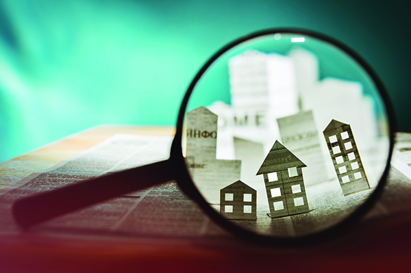 Image of a magnifying glass showing small buildings cut out of paper