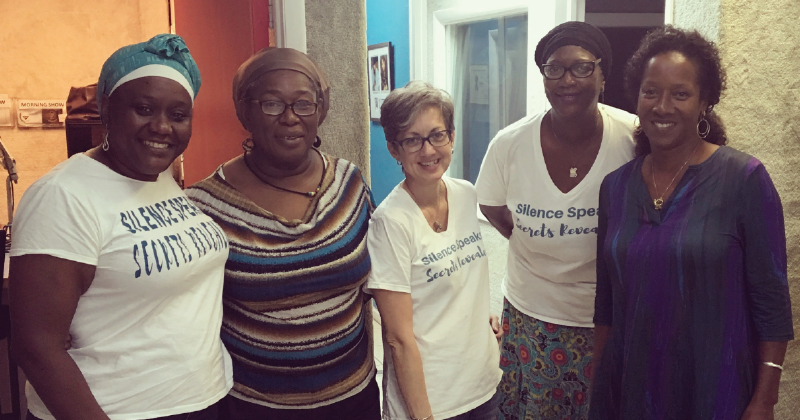 Five women, several of them wearing t-shirts that say "Silence Speaks, Secrets Revealed"