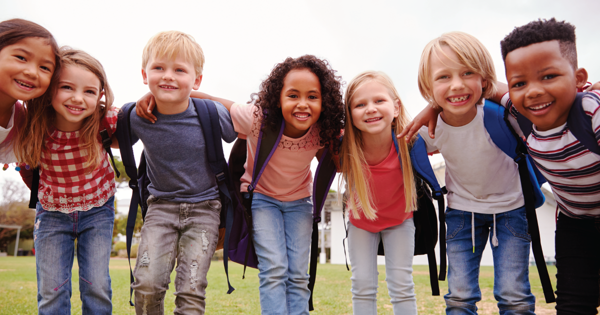 Smiling elementary school children wearing backpacks