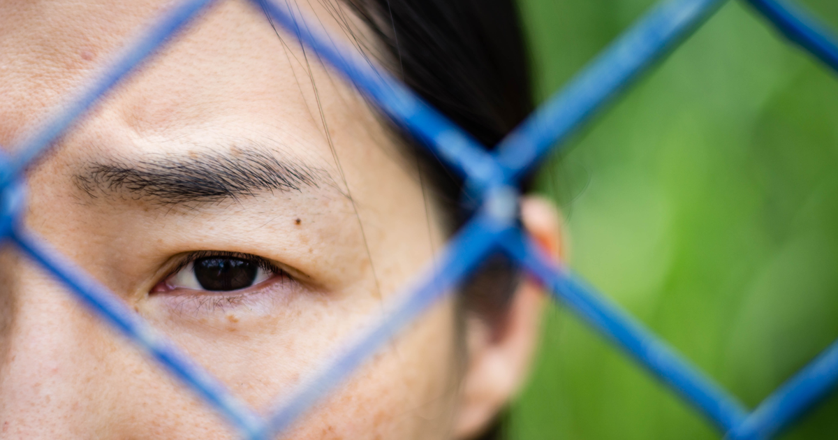 Woman looking through a chain-link fence