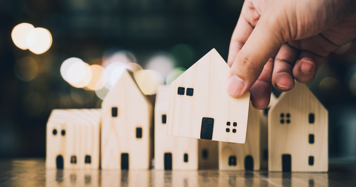 Person holding small wood cutout of a house