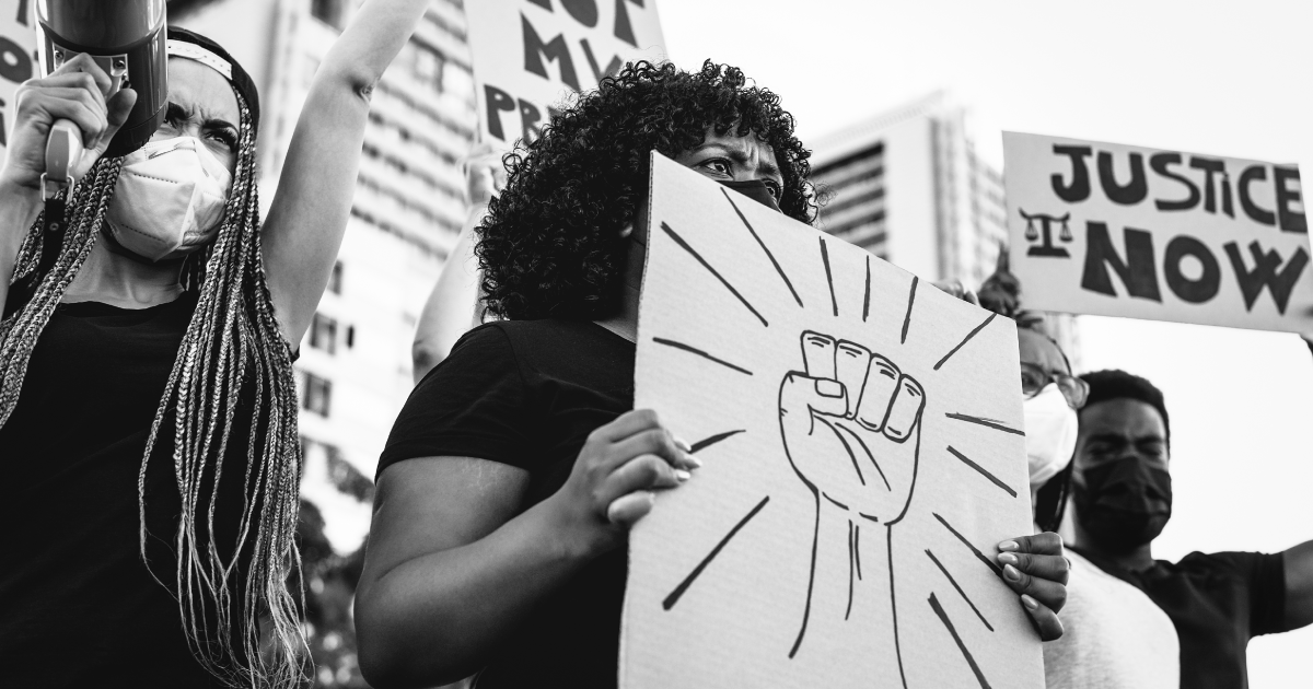 People at a protest holding a sign with a raised fist