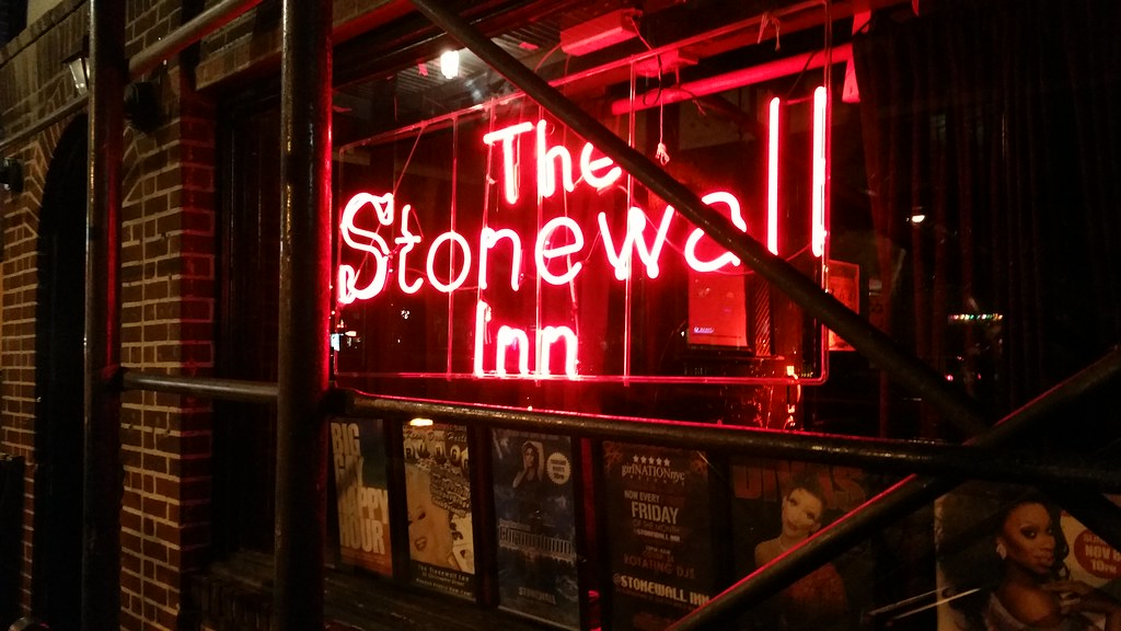Picture of The Stonewall Inn sign in the window, glowing in red at night