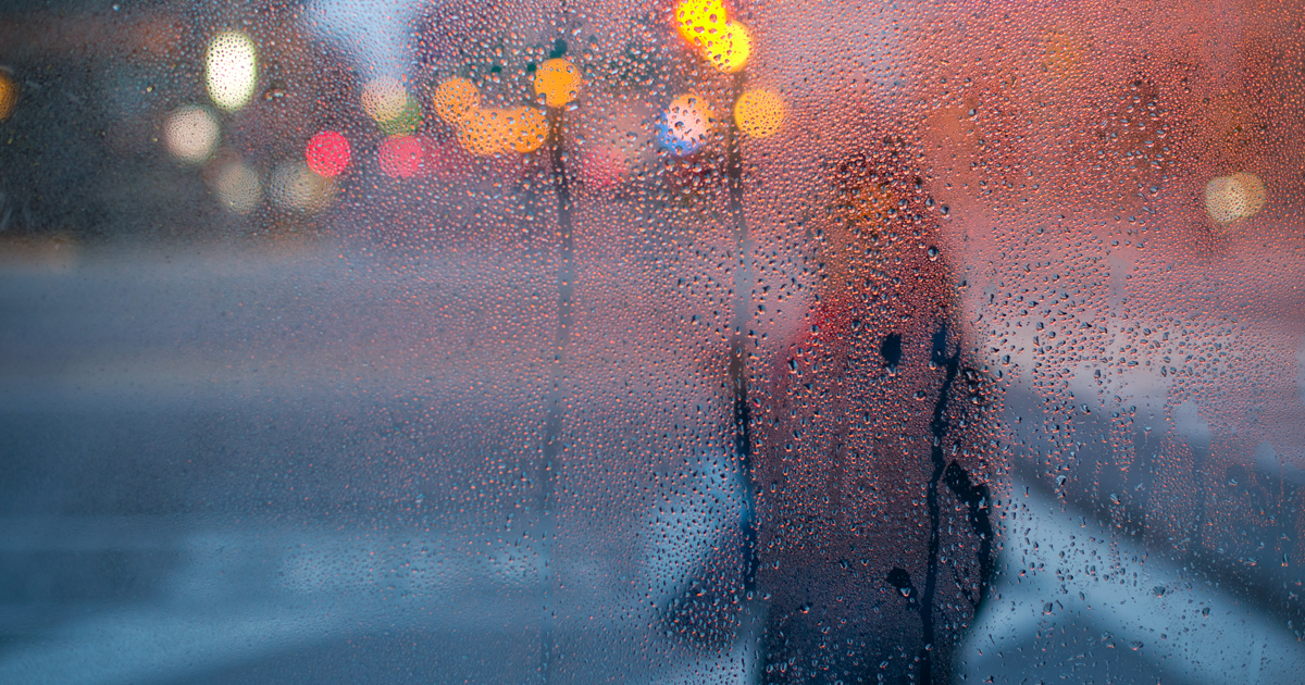 imagen borrosa de una persona a través de una ventana lluviosa