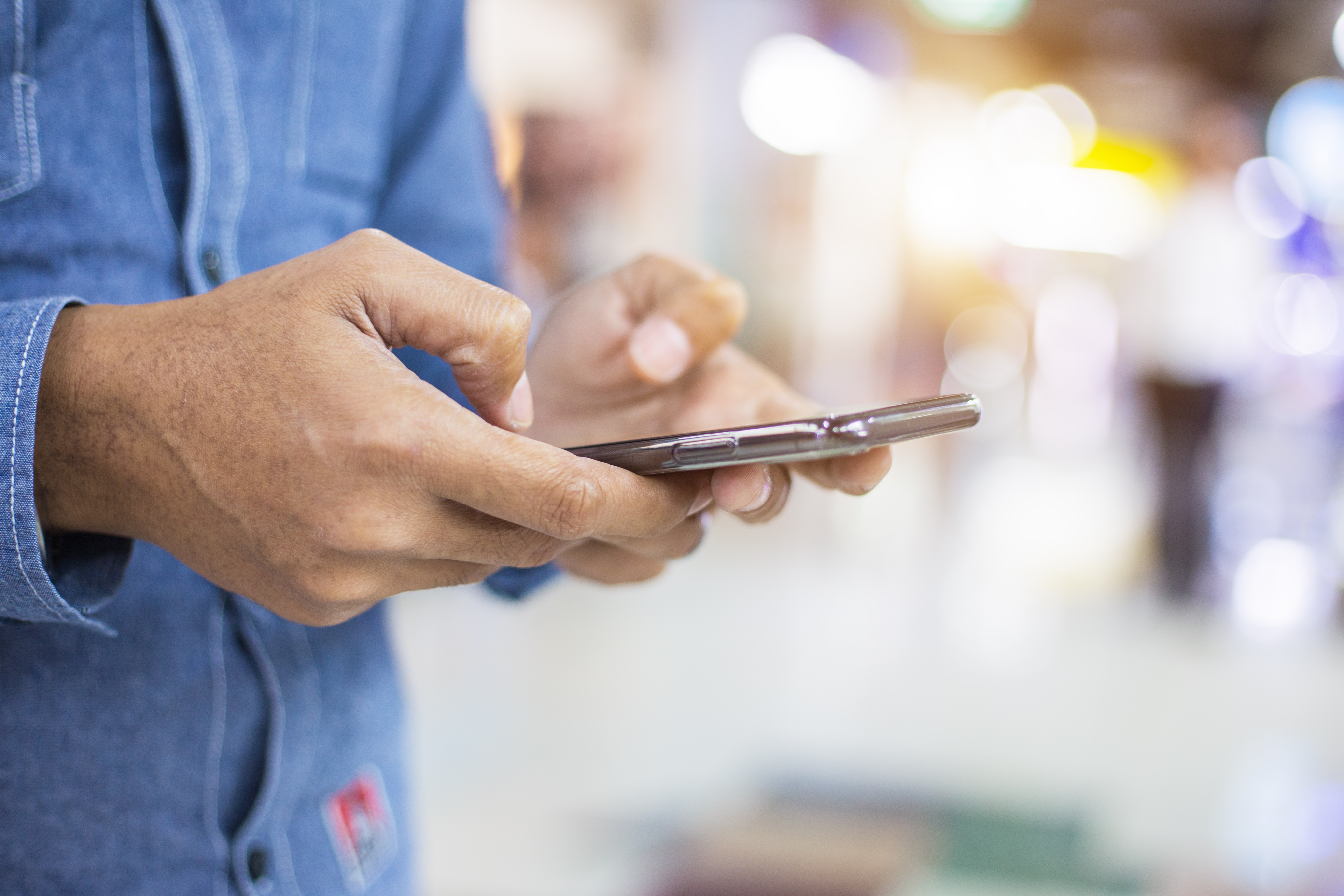 photo of hands holding a phone texting in public