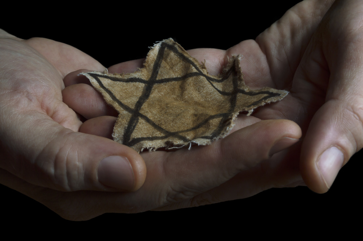 image shows hand holding a tattered jewish star