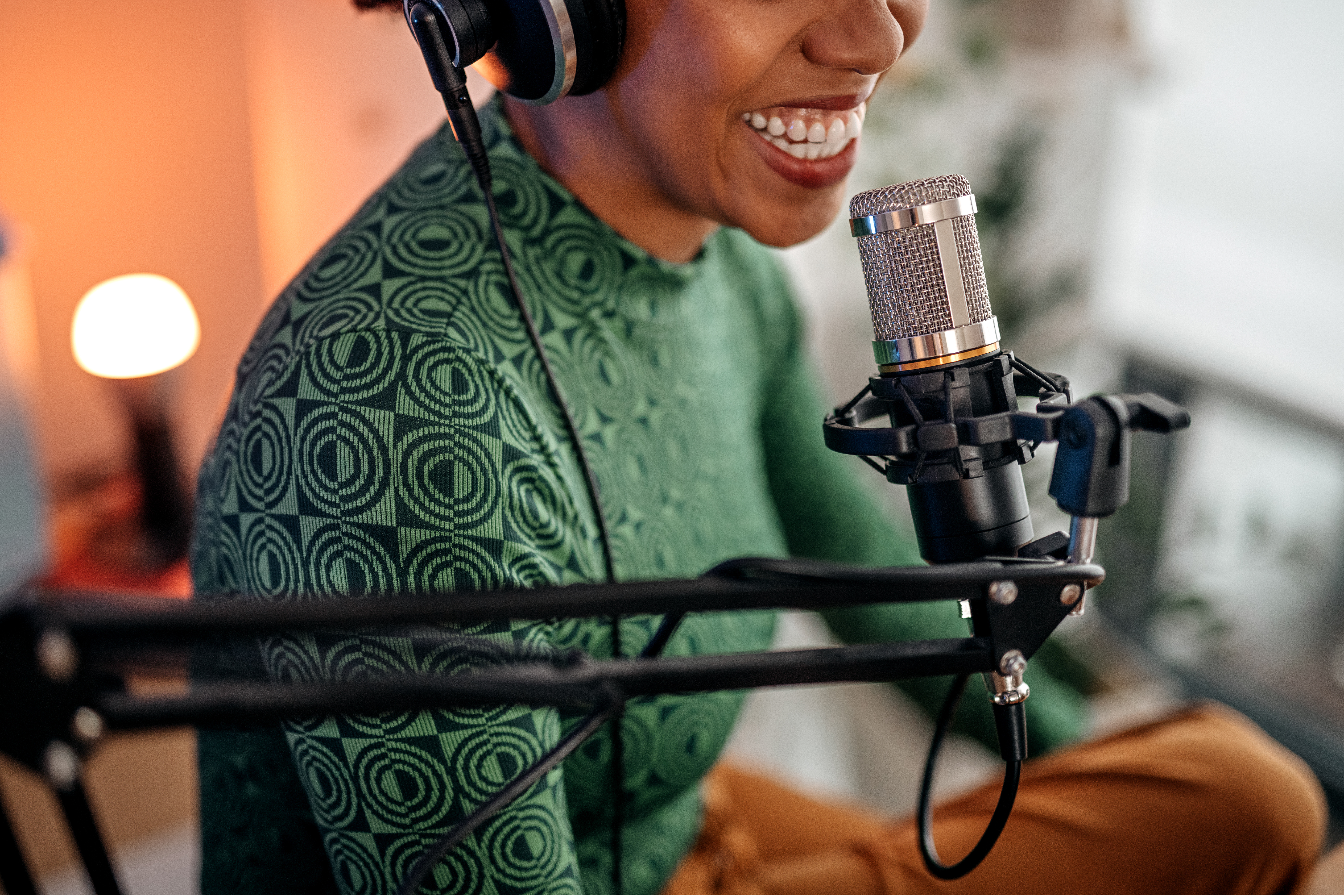 a woman smiles while talking into a microphone with headphones on