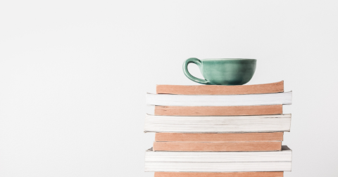 stack of books with a cup of tea resting on top