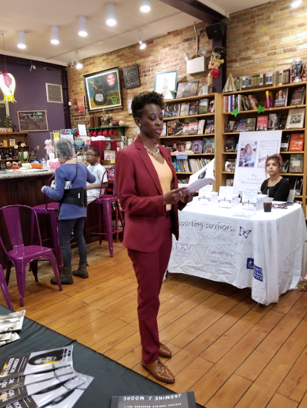 A woman reads her book aloud to an audience.