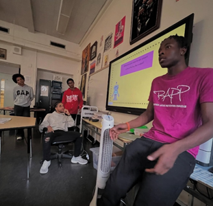Student with pink RAPP shirt speaking in front of a class